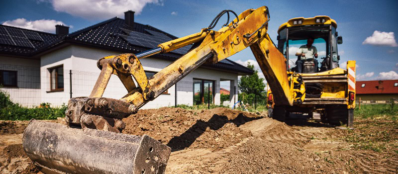 Bagger auf einer Hausbaustelle - Ausheben der Fundamente für ein modernes Haus